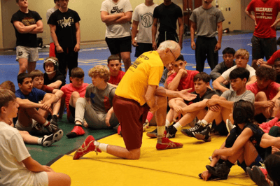 Assistant coach giving a technical training talk on wrestling techniques.