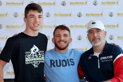 Zain Retherford posing with a camper and another assistant coach.