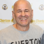 Coach Ricky Bonomo in front of a banner for Ken Chertow's Gold Medal Training Camps. 
