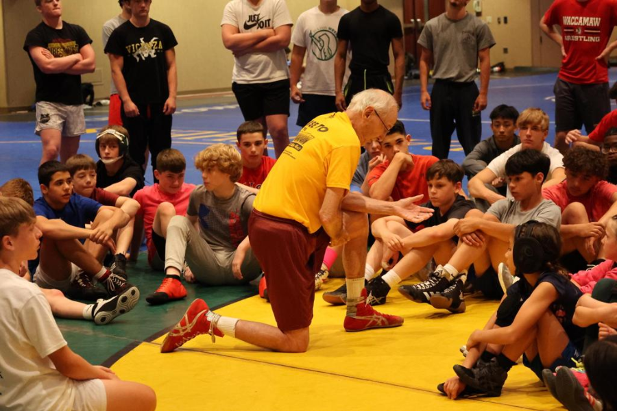 Assistant coach giving a technical training talk on wrestling techniques.