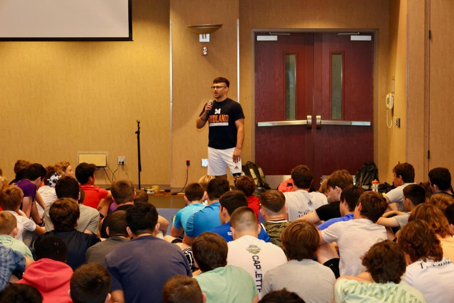 Assistant coach discussing wrestling techniques at camp. 