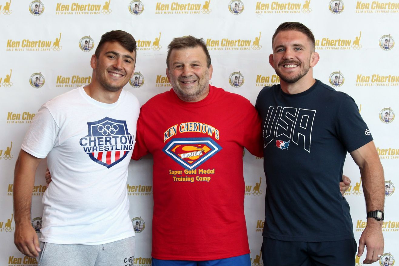 Ken Chertow in a red Gold Medal Training Camp shirt between Pat Glory and Zain Retherford at his summer wrestling camp