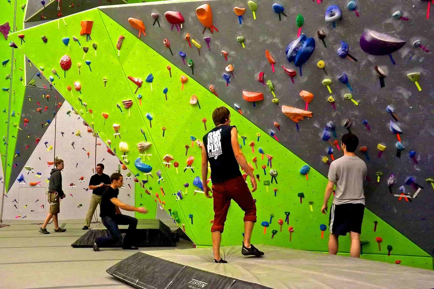 Climbers on the bright green walls of the Pennsylvania climbing gym at Ken Chertow's wrestling camp venue