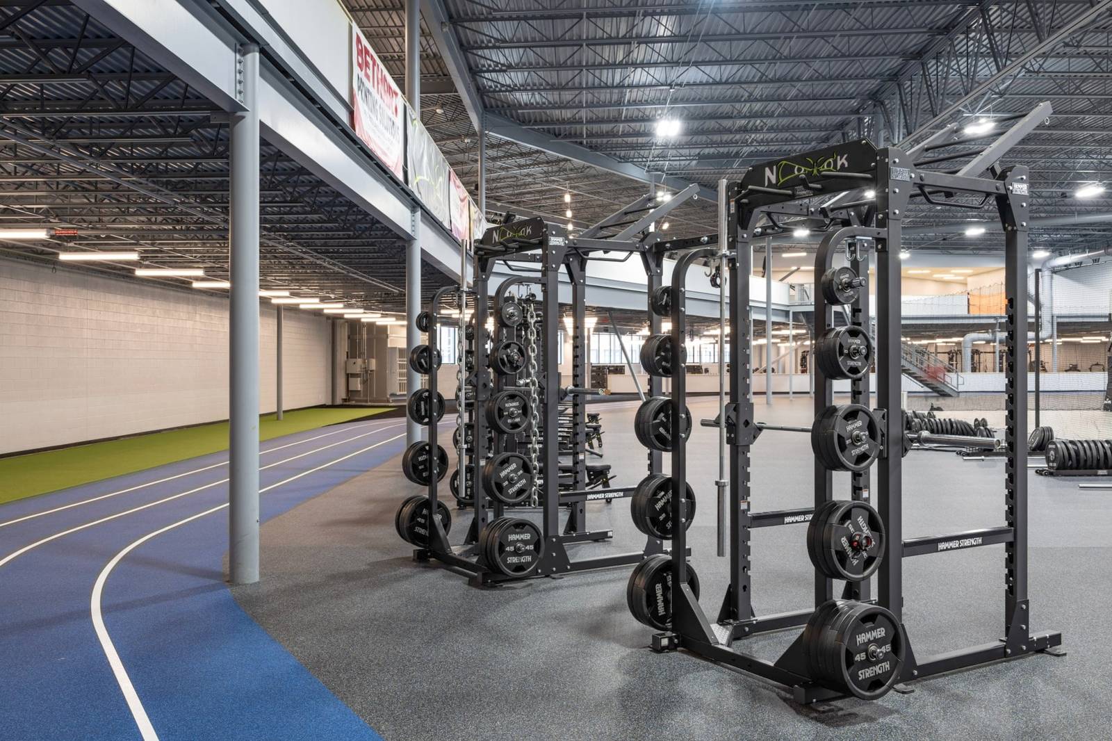 Squat racks loaded with plates beside the indoor track at Champion Mill, Ken Chertow wrestling camp's Ohio venue