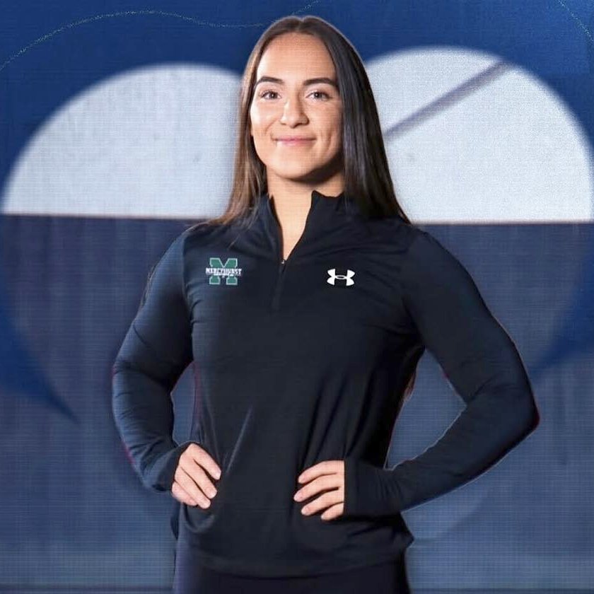Alexia Wagner, hands on hips, in a black Mercyhurst quarter-zip, a Ken Chertow summer wrestling camp clinician