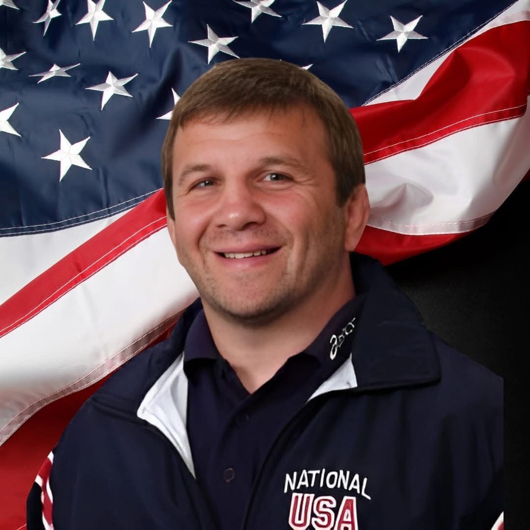 Ken Chertow in a Team USA jacket in front of the American flag, host of Ken Chertow Gold Medal Training Camp