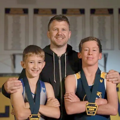 Matt Kocher with his two sons, both wearing Keystone State medals, coach at Ken Chertow's summer wrestling camp