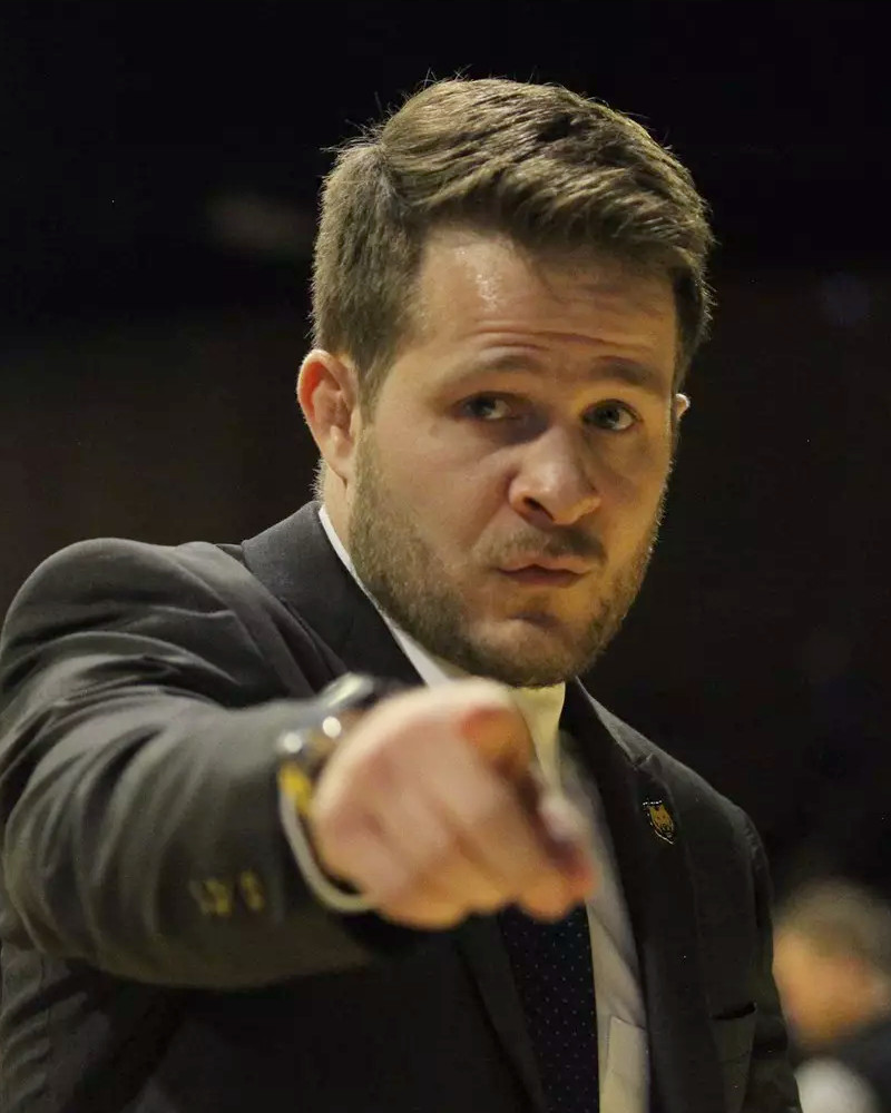 Troy Nickerson pointing from the side of the mat in a suit, on the coaching staff at Ken Chertow Gold Medal Training Camp