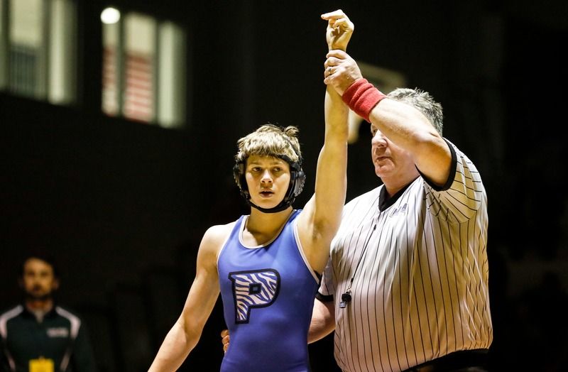 Ava Rose in a blue singlet with her arm raised by the referee