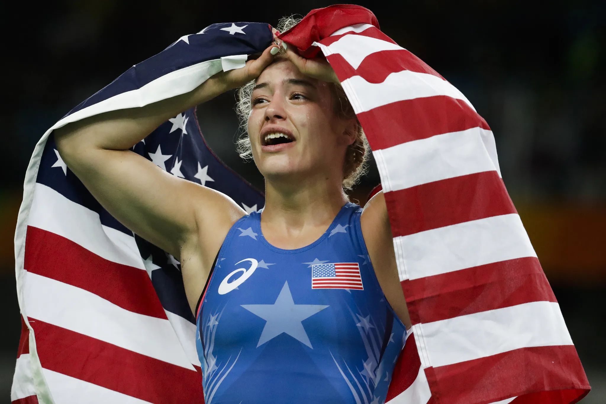 Helen Maroulis with an American flag over her shoulders, overcome after an Olympic win